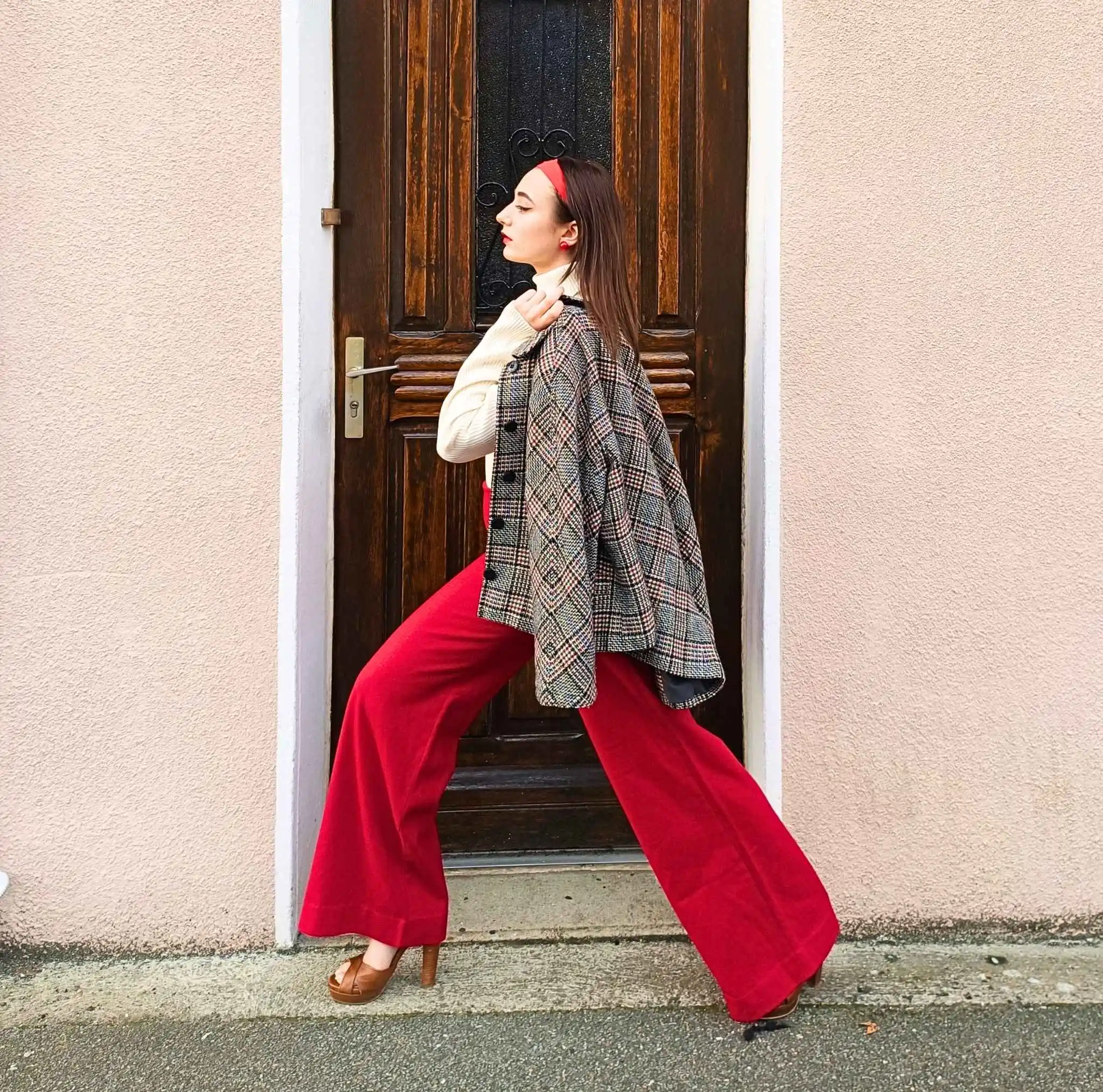 Femme marchant dans la rue avec allure, habillée d'un pantalon rouge vintage années 70.