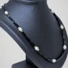 Zoom sur le collier vintage de perles noires et blanches nacrées, vue de côté.