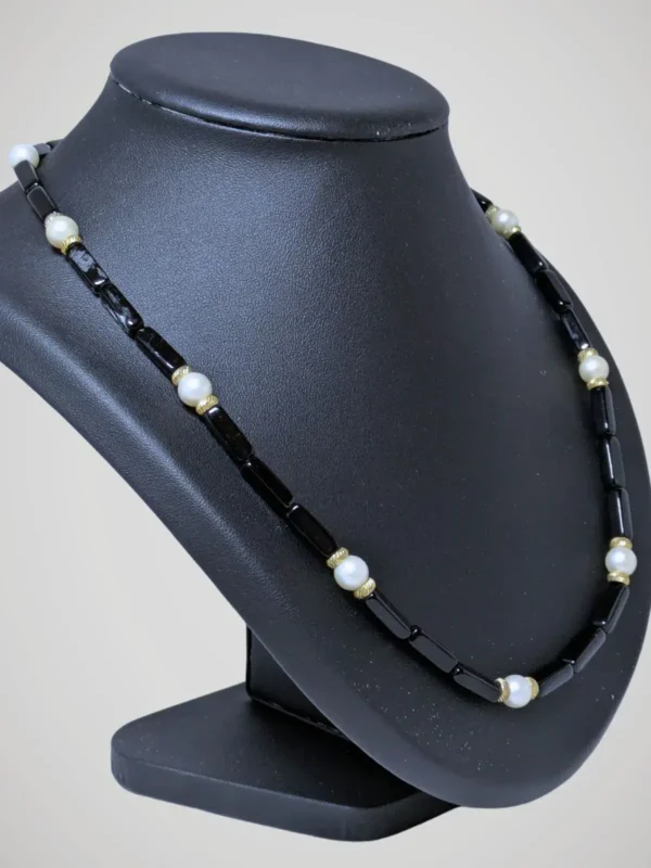 Zoom sur le collier vintage de perles noires et blanches nacrées, vue de côté.