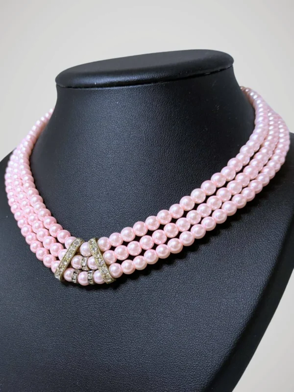 Zoom sur le collier vintage à trois rangs de perles roses nacrées et brillants, vue de côté.