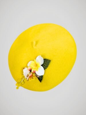 Béret en laine jaune orné d'une broche modèle jonquille fait main, vue de côté.