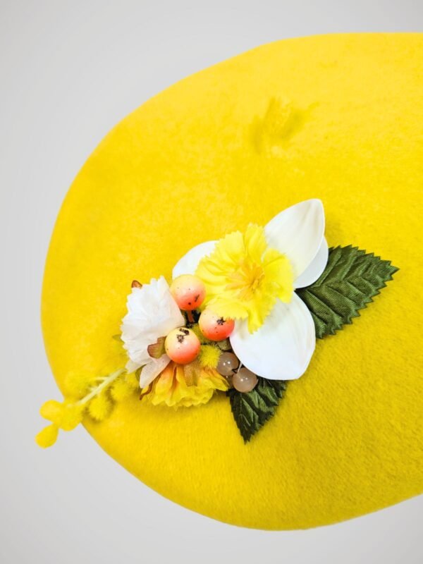 Zoom sur le béret en laine jaune orné d'une broche modèle jonquille fait main.