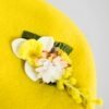 Deuxième zoom sur le béret en laine jaune orné d'une broche modèle jonquille fait main.