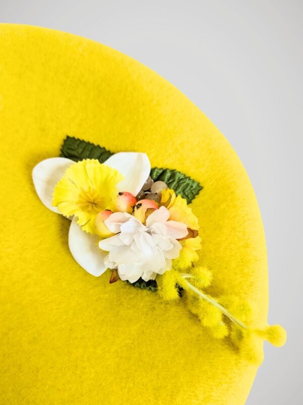 Deuxième zoom sur le béret en laine jaune orné d'une broche modèle jonquille fait main.