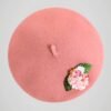 Béret en laine rose orné d'une broche modèle fleurs de cerisier fait main, vue de face.