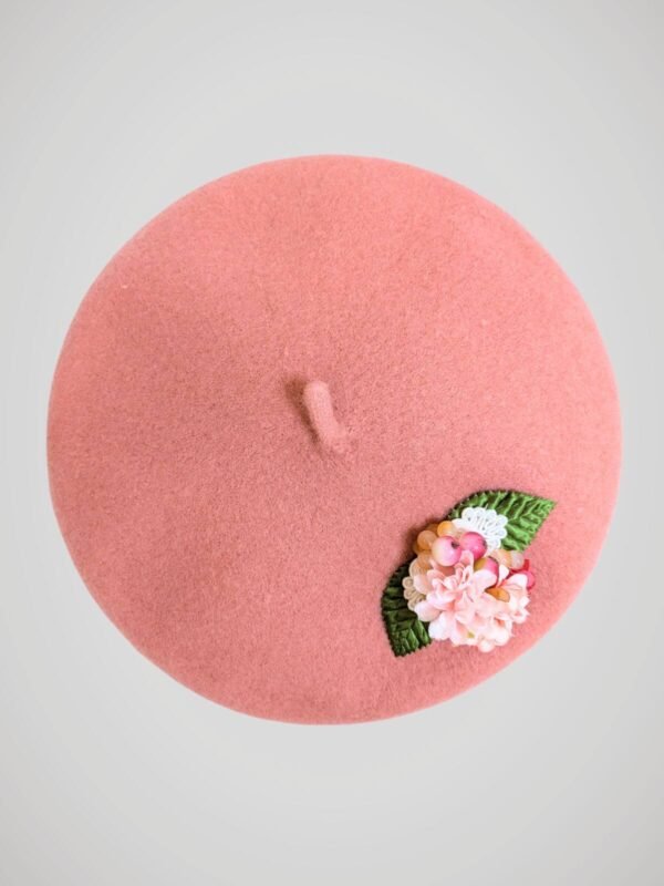 Béret en laine rose orné d'une broche modèle fleurs de cerisier fait main, vue de face.