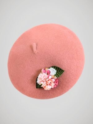 Béret en laine rose orné d'une broche modèle fleurs de cerisier fait main, vue de côté.