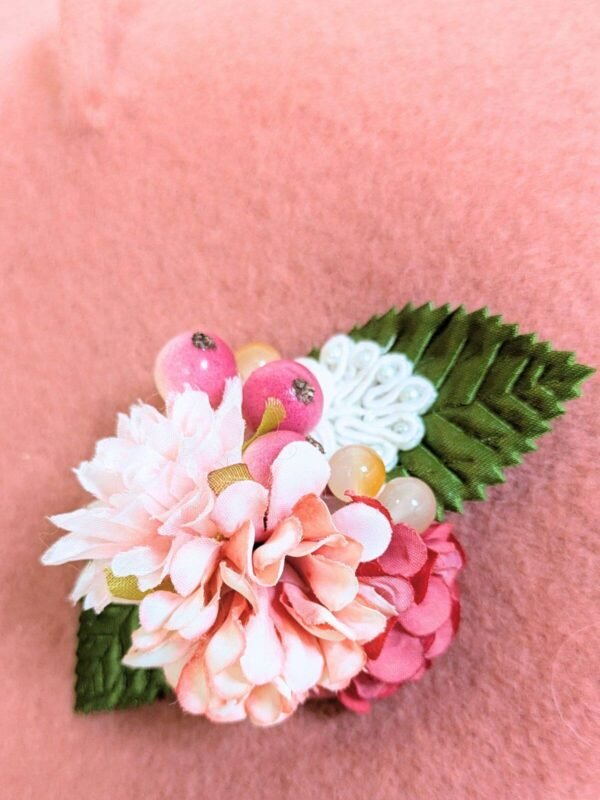 Zoom sur le béret en laine rose orné d'une broche modèle fleurs de cerisier fait main.