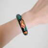 Bracelet jonc vintage noir peint à la main de motifs floraux colorés, en bois, porté et vue de face.