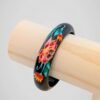 Zoom sur le bracelet jonc vintage noir peint à la main de motifs floraux colorés, en bois.
