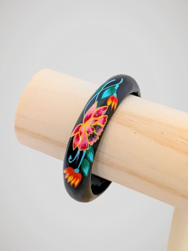 Zoom sur le bracelet jonc vintage noir peint à la main de motifs floraux colorés, en bois.