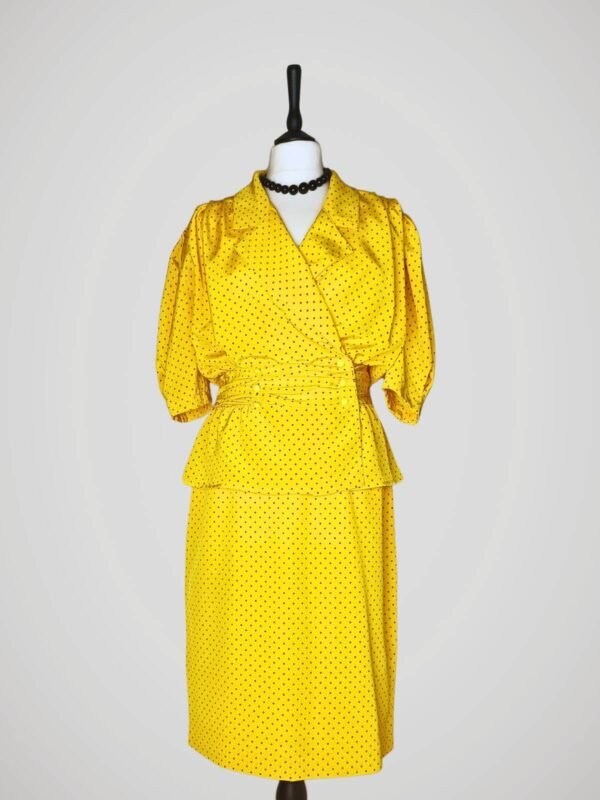 Ensemble composé d'une jupe tailleur et d'un chemisier manches courtes, vintage des années 80, jaune à pois noirs pour femme, taille M à L, vue de face.