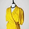 Zoom sur l'ensemble composé d'une jupe tailleur et d'un chemisier manches courtes, vintage des années 80, jaune à pois noirs pour femme, taille M à L.