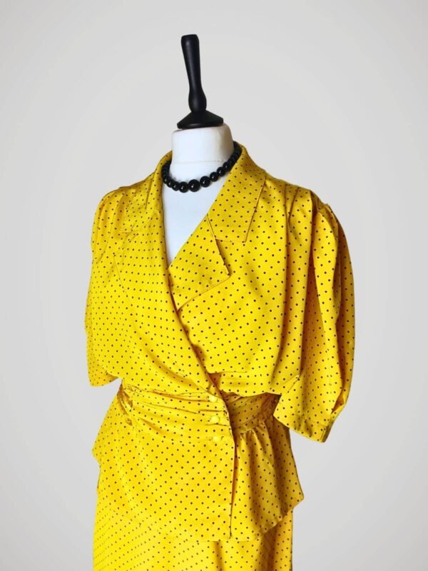 Zoom sur l'ensemble composé d'une jupe tailleur et d'un chemisier manches courtes, vintage des années 80, jaune à pois noirs pour femme, taille M à L.