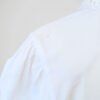 Zoom sur la tâche de la chemise à manches courtes blanche à boutons nacrés, pour femme, vintage des années 80.